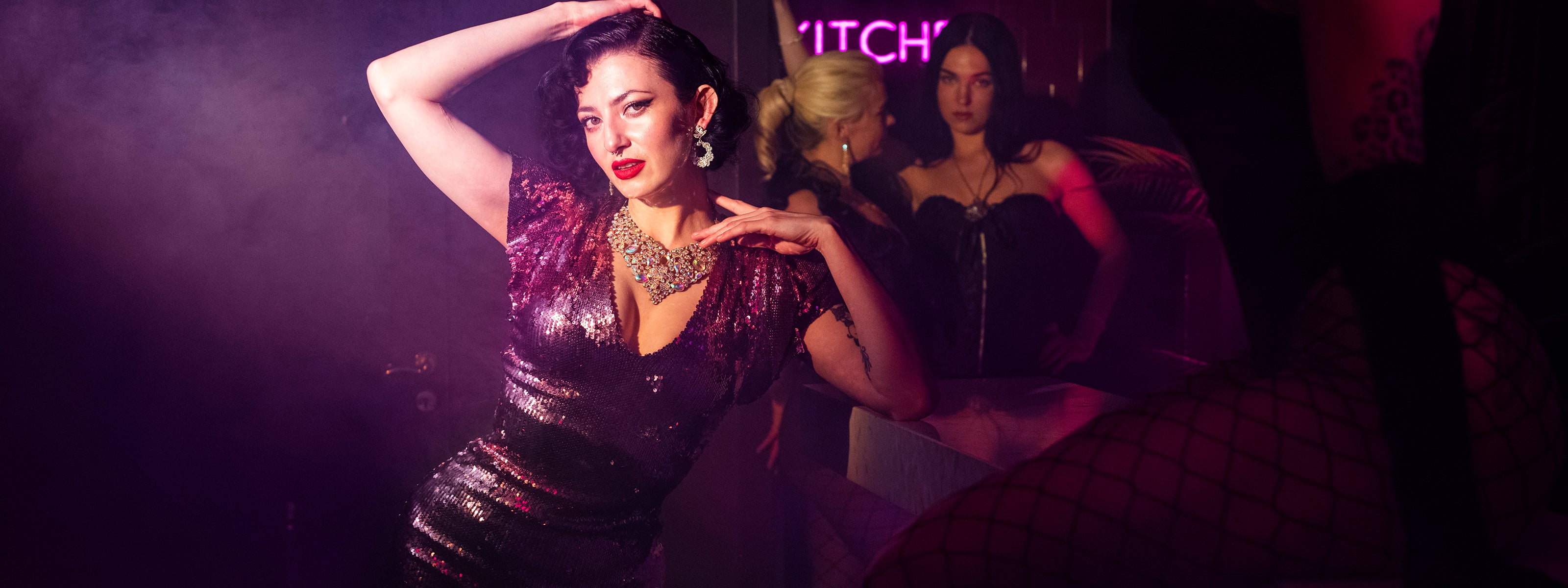 Glamorös dansare i paljettklänning uppträder i neonbelyst klubbmiljö på nattklubben Velvetroom i Stockholm.