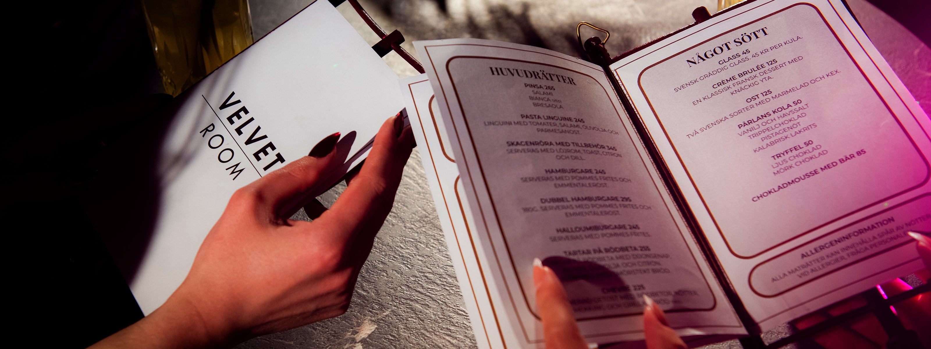 Gäster tittar i menyn vid bord på nattklubben Velvetroom i Stockholm i exklusiv klubbmiljö.