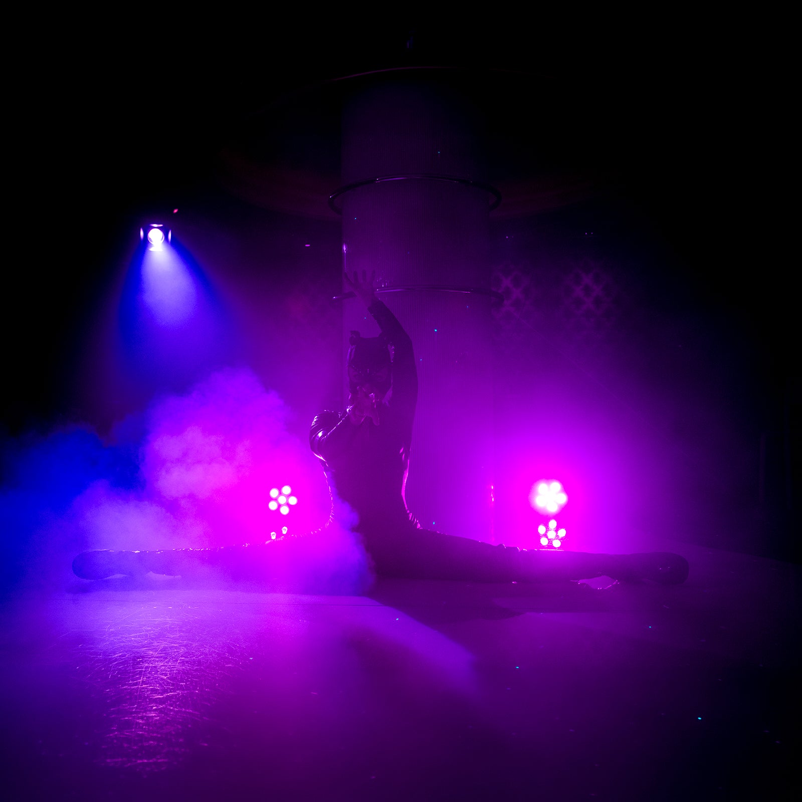 Showdansare i catsuit gör spagat på scen i neonljus och rök på nattklubben Velvetroom i Stockholm.