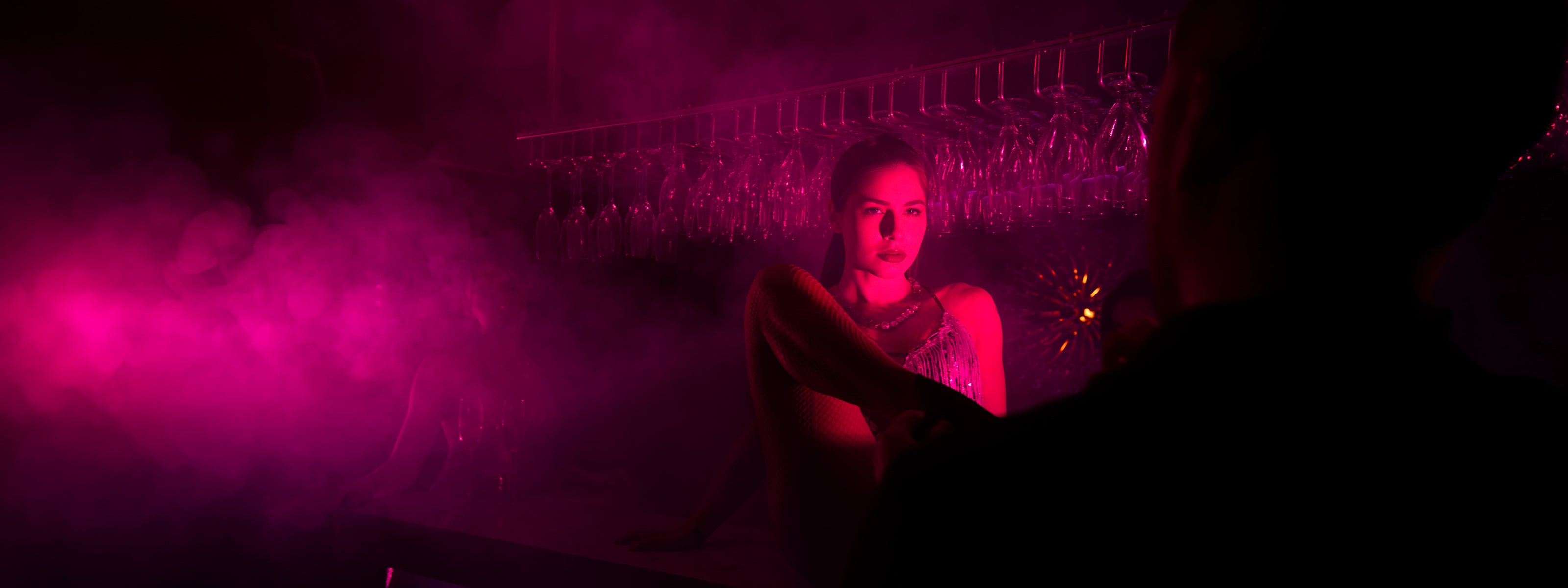 Showdansare vid bar i röd neonbelysning i nattklubbsmiljö på Velvetroom i Stockholm.